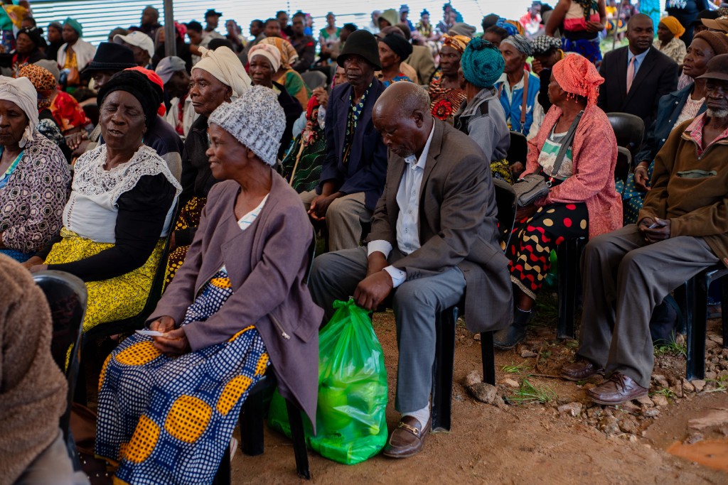 Elderly residents seated with hampers at the distribution
